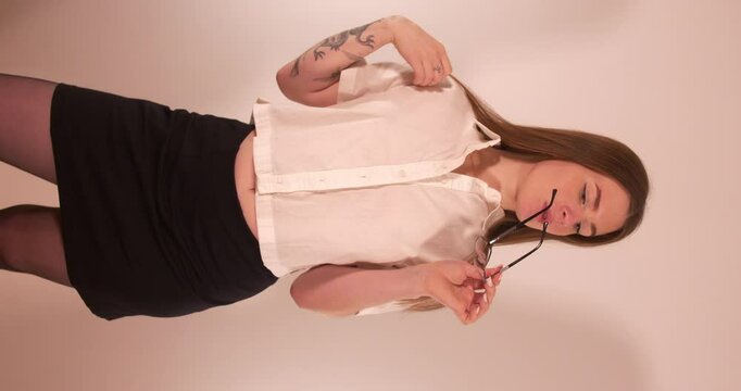 Sexy beautiful Girl grooming herself and playing with glasses while teasing and smiling. Vertical shot