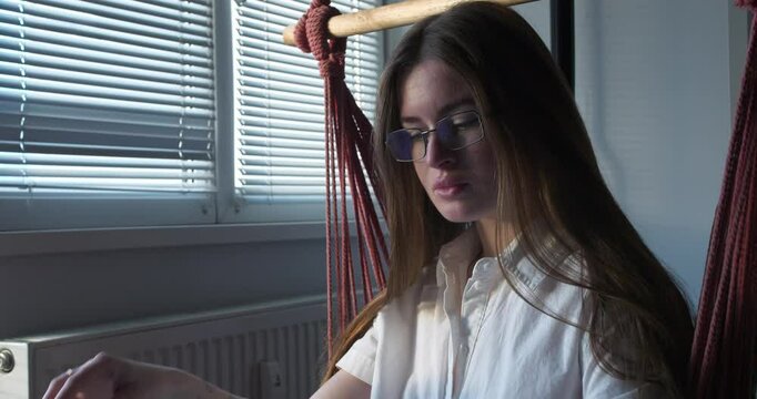 Beautiful Sexy girl with glasses reading a book while seating on a swing. Tilt up Medium close up