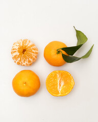 oranges and tangerines with leaves whole and in size lie on a white background
