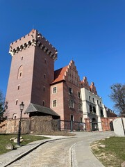 Old architectural building with red brick walls, ancient castle, trees around. The Royal Castle in Poznan, the oldest preserved royal residence in Poland. 