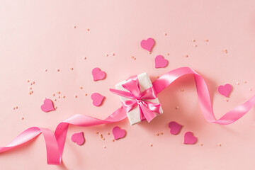 Pink hearts and gift box with ribbon on a light pink background