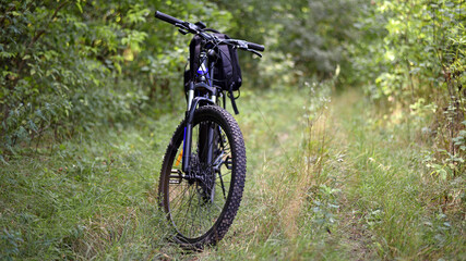 Naklejka premium bike. transport. summer or autumn time. mountain bike. A mountain bike stands on a trail in a summer forest. cycling outdoor. concepts of sports, cycling, outdoor activities. spring park. front view