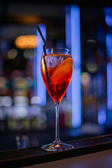 Close up of cold drink in a dark night bar, italian aperol spritz, wine-based cocktail, consists of Prosecco wine, digestive bitters, soda water and oranges.