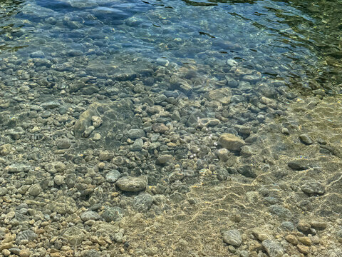 Crystal clear water with pebbles and stones on sea shore