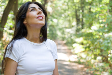 Beautiful  woman relaxing and breathing fresh air with sunlight in the summer park