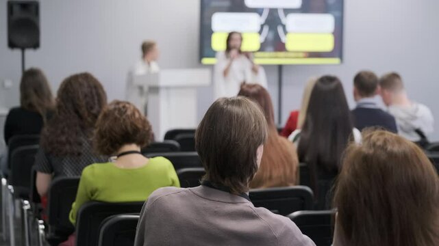 Audience attentively listening to speakers during business presentation at conference. Engaging session with visible interaction.