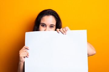 Woman holding a blank poster in front of her face.