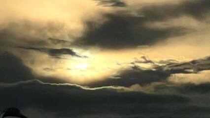 The sun behind the clouds in dark sky. 