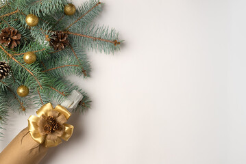 Christmas tree branch with decorations and wrapped champagne bottle with bow on white background. Flat lay, top view. Copy space