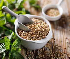 Green buckwheat groats in a ceramic bowl, close up view,