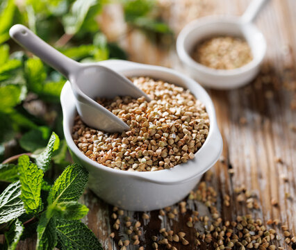 Green buckwheat groats in a ceramic bowl, close up view,