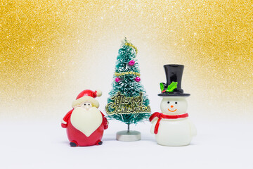 Cute little snow man and Santa Clause with Christmas tree over blurred gold glitter background, Christmas card background idea