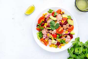 Mexican style salad with tuna, avocado, corn, beans, tomatoes and cilantro, white background, top view