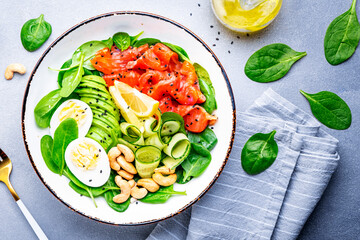 Keto diet salad with salmon, avocado, spinach, eggs and cashew. Gray table background, top view