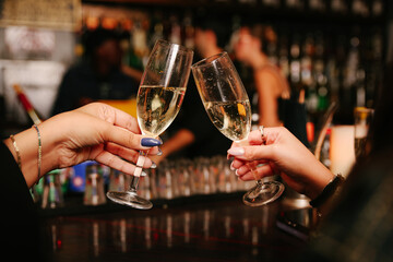 women's hands cheers with glasses of champagne