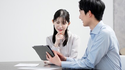 Obraz premium タブレットで資料を見る男女