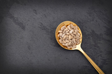 Fototapeta premium Helianthus annuus - Raw and dried sunflower seeds in a spoon.