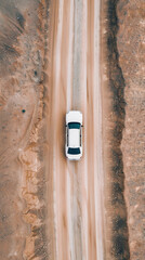 Dynamic aerial view of a rally car navigating a dirt track, leaving skid marks in its wake, set against a rugged mountain backdrop, perfectly capturing the spirit of speed, adventure, and motorsport.