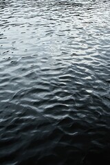 Fototapeta premium A black water surface with rippling waves, providing ample copy space.