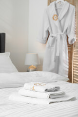 Bed with clean linens, pillow, towels and bathrobe indoors