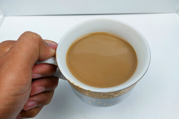 Milk coffee is held to drink on a white table