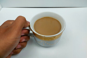 Milk coffee is held to drink on a white table