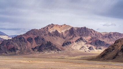 Scenic landscape view of purple pink mountain in high altitude desert along Pamir Highway on overcast day, Murghab, Gorno-Badakhshan, Tajikistan