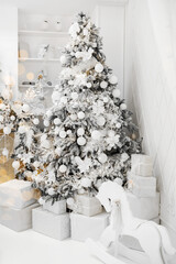 Stylish white Christmas tree surrounded by gift boxes in a cozy winter setting