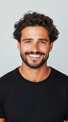 Obraz premium Smiling man with curly hair wearing black shirt against gray wall