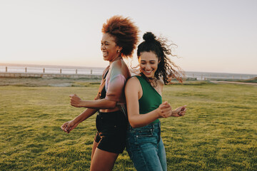 Two Gen Z friends dancing in the park, capturing joyful and carefree moments to share on social media