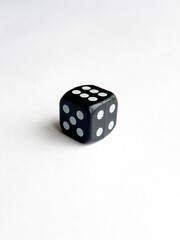 Black six sided dice on white surface with five dots