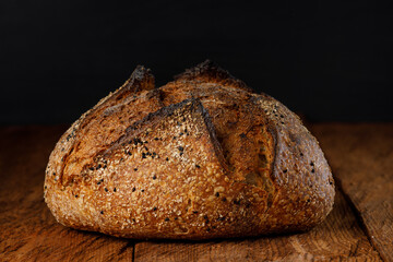 Crispy artisan sourdough bread with seeds on rustic wooden table