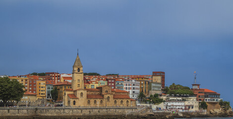 A old town in Gijon, with a large church and a tall tower.