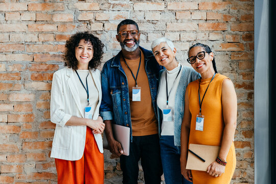 Group of professionals smiling and standing together in front of a brick wall