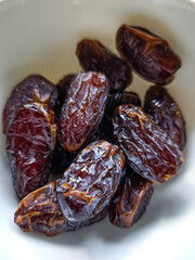 Juicy medjool dates resting in white bowl, ready for consumption