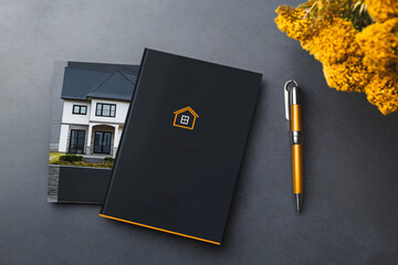 Customizable real estate brochure mockup laying on a desk with a pen and flowers, showcasing a modern house