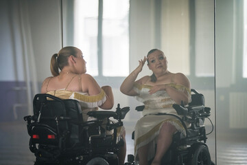 Young woman, a wheelchair dancer checking her look in a mirror at a dance studio before performance. Dancing with disability concept.