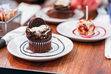 Delicious Chocolate Cupcake Topped With Cream and Cookie on a Plate With Dessert Selection for Sweet Treats Moment