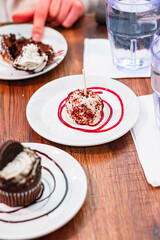 Delicious Dessert Selection Featuring Cake Pops and Cupcakes on White Plates with Colorful Syrup Drizzles, Set on a Rustic Wooden Table in a Casual Dining Atmosphere