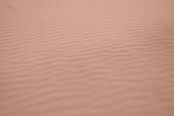 Background made of Wavy desert sand texture. Fine beach sand. Color Of The Year 2025 - Mocha Mousse