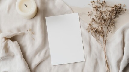 Elegant blank invitation card mockup featuring dried flowers and a candle on a soft beige surface showcasing a minimalistic design.