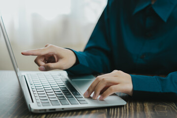 person using laptop with focused expression, pointing at screen. setting is bright and modern, emphasizing productivity and technology