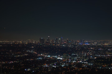 Obraz premium The Los Angeles skyline is visible at night, featuring illuminated skyscrapers and extensive city lights, highlighting the vibrant downtown area.