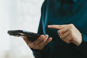 person using smartphone, tapping screen with finger, wearing dark shirt. image conveys sense of...