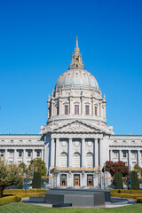 Obraz premium San Francisco City Hall stands with its grand dome and intricate facade under a clear blue sky, surrounded by gardens and pathways in the civic center.