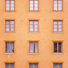 Vibrant Orange Apartment Building Facade With Symmetrical Wooden Framed Windows Featuring Minimalist Design And Urban Architecture Elements For Modern City Living And Aesthetic Appreciation