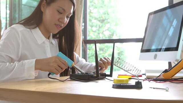 A man and a woman are working on a project together. The woman is holding a tool and the man is looking at a computer monitor. Scene is collaborative and focused