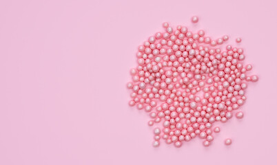 Holidays concept. Decorative small pink balls on a pink background. Top view. Copy space.
