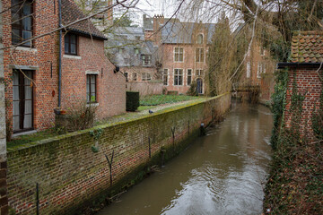 Quaint canal lined with moss-covered brick walls and historic buildings.  A pigeon rests on the wall.