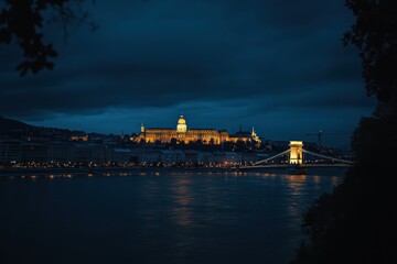 Fototapeta premium a dark blue sky and yellow light on the castle in front of the chain bridge